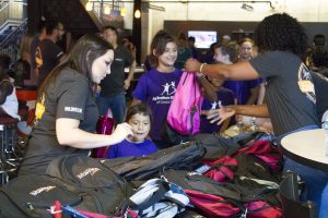 Big for a Day Desert financial credit union volunteers giving backpacks to waiting littles